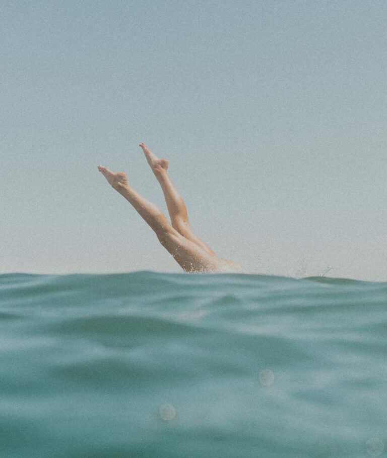 Beine einer ins Meer eintauchenden Person